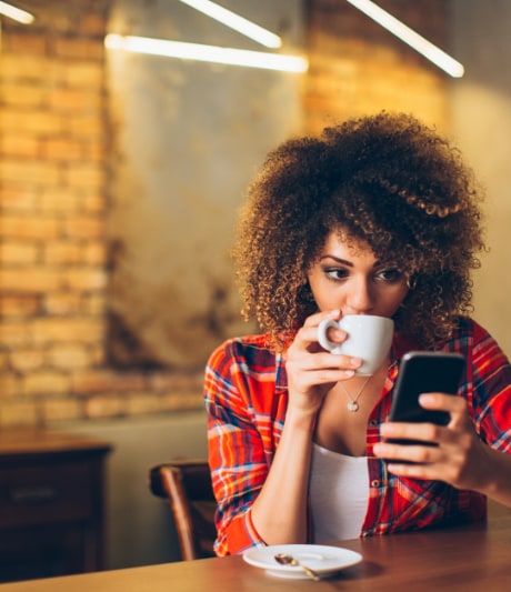 Woman Sipping Coffee While Looking At Phone
